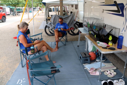 Dos turistas sentados en una parcela del camping La Noguera de Sant Llorenç de Montgai