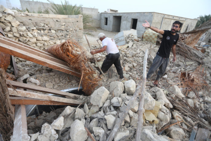 Dos homes busquen entre la runa de casa seua al llogaret de Sayeh Khvosh després del sisme.