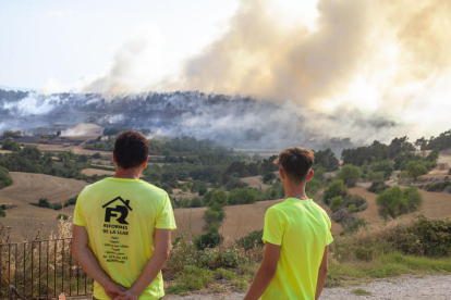 Dos hombres observando el avance del fuego desde el pueblo de Belltall, en la Conca de Barberà. 