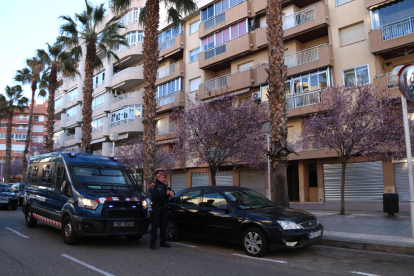 Una furgoneta de los Mossos d'Esquadra y un agente haciendo guardia delante de uno de los edificios registrados en Salou en el marco del operativo conjunto con la Europol en Tarragona y Andalucía contra una banda dedicada a falsificar moneda.