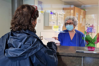 Una profesional de la Fundación Sant Hospital de la Seu d'Urgell entrega el documento con la baja médica al familiar de un paciente.