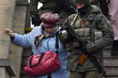Un soldado ayuda a una mujer que baja unas escaleras en Lviv.