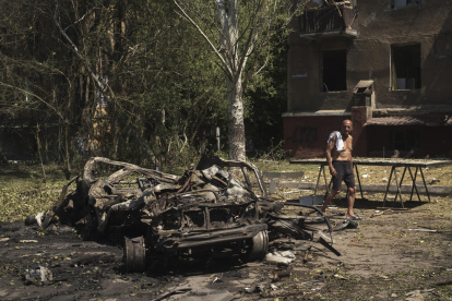 Un home passeja al costat d’un cotxe calcinat a Donetsk.