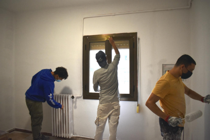 Tres de los jóvenes durante los trabajos de rehabilitación en una de las viviendas.