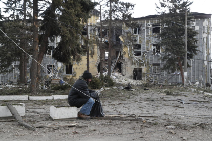 Un hombre sentado frente a un edificio destrozado por las bombas en Volnovakha, en el Donetsk.