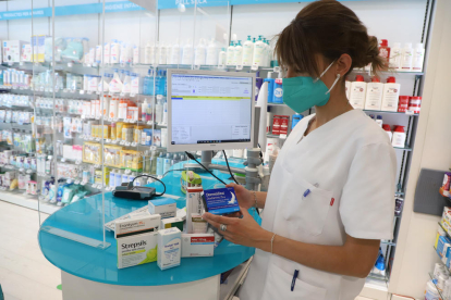 Una empleada de la farmacia Garròs de Lleida, con algunos de los medicamentos más vendidos.