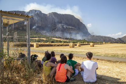En el incendio de Peramola trabajaron ayer 55 dotaciones terrestres y 9 aéreas. A la derecha, jóvenes contemplando el humo.