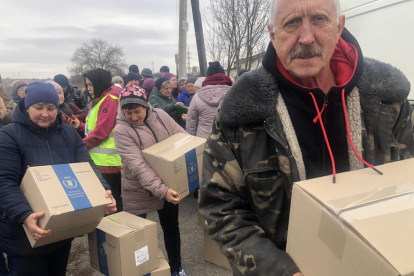 Varias personas recogiendo las cajas que les entrega el reparto de la ayuda humanitaria en Hnilytsia.