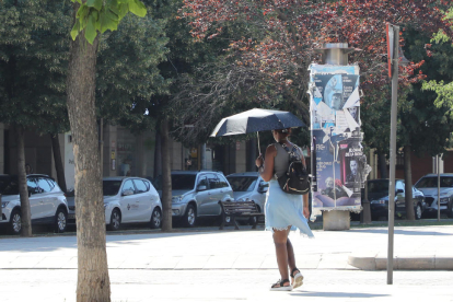 Una dona protegint-se del sol amb un paraigua ahir a la tarda a la ciutat de Lleida.