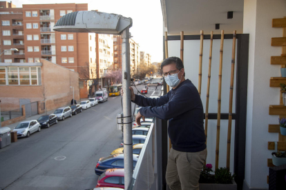 El vecino agarrando la farola situada a escasos centímetros de su balcón.