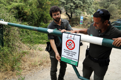 Dos Agents Rurals col·locant un cartell de prohibició del pas al Montsec a la zona de Corçà per l'activació del pla Alfa 3