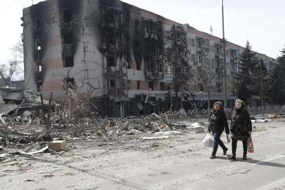 Residentes de Mariupol caminan entre edificios atacados por las tropas rusas.