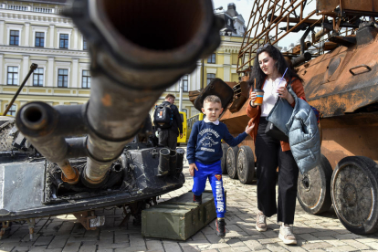 Civils ucraïnesos observen restes militars russes exposades al centre de Kíiv.