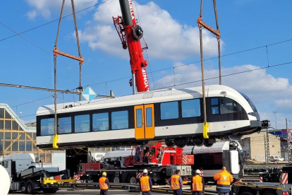 Operaris descarreguen la tercera unitat de tren de la línia Lleida-la Pobla a l'estació del Pla de Vilanoveta de Lleida