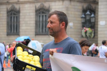 Un dels pagesos de Lleida, amb una caixa de pomes, aixecant una pancarta durant la protesta davant de la Generalitat