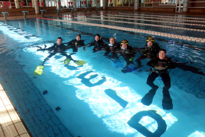 Bussejadors i bombers de Lleida despleguen una pancarta dins l'aigua per conscienciar sobre la salut masculina