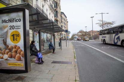 Ciudadanos esperan en una parada del bus en Lleida.