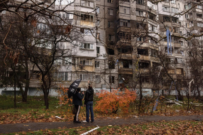 Dos ciudadanos ucranianos delante de un edificio dañado por bombas rusas en Jersón.