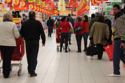 Clientes llenando la cesta de la compra en un supermercado.