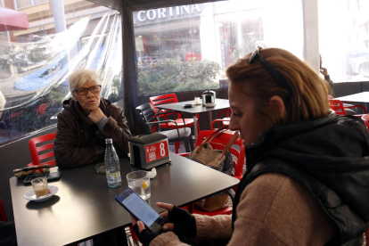 Una mujer consulta el mensaje de Protección Civil en la terraza de un bar en La Pobla de Segur.  