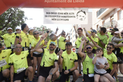 Unos corredores señalan la pancarta bajo el arco de salida y llegada recordando la figura de Garra.