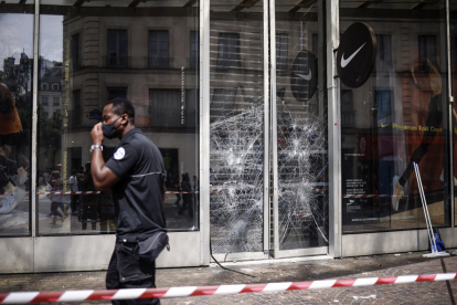 Un guàrdia de seguretat passa davant un aparador trencat d'una botiga després dels disturbis a París.