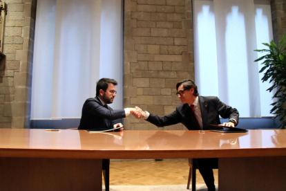 El presidente de la Generalitat, Pere Aragonès, y el primer secretario del PSC, Salvador Illa, se dan la mano después de firmar en la Sala de Diputados del Palau de la Generalitat el acuerdo por la aprobación de los presupuestos del Govern de 2023.
