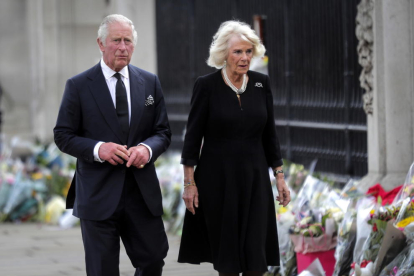 El rei Carles III i Camila, la reina consort, miren els tributs florals deixats fora del Palau de Buckingham aquest divendres.