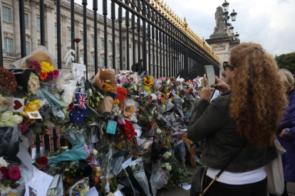 Una mujer hace fotografías a las flores en recuerdo a la reina Isabel II en el Buckingham Palace.
