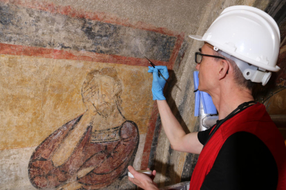 Un dels restauradors pintant el fragment de Caín incorporat al mural.