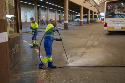 Un operari netejant un embornal a l’interior de l’estació d’autobusos de Lleida i d’altres, pintant la façana del carrer Saracíbar.