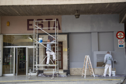 Un operari netejant un embornal a l’interior de l’estació d’autobusos de Lleida i d’altres, pintant la façana del carrer Saracíbar.