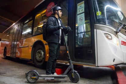 Usuario de un patinete eléctrico leyendo un cartel que informa de la nueva normativa.