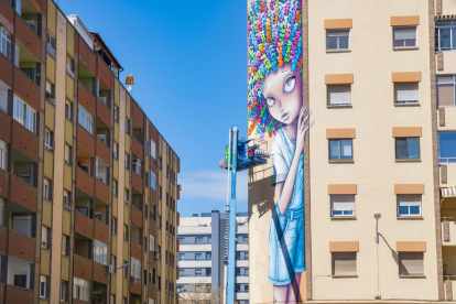 L'artista Vinie realitzant els últims traços al seu mural al carrer Dr. Zammenhoff.