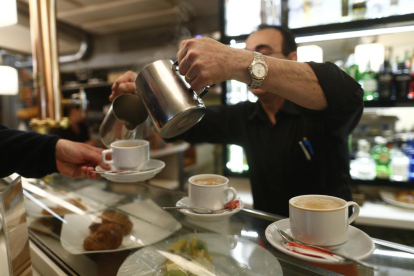 Un camarero sirviendo cafés en una fotografía de archivo.