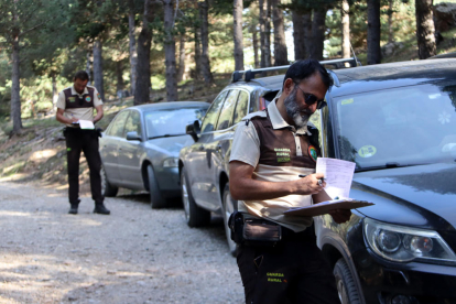 Una pareja de guardas rurales multando varios vehículos a una pista forestal de Riu de Cerdanya