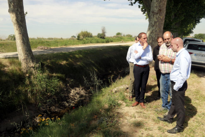 El subdelegado del gobierno español en Lérida, José Crespín, el delegado del gobierno español en Cataluña, Carlos Prieto, y el responsable de regadíos de UP, Jaume Pedrós, al lado de un tramo de la segunda acequia principal del canal de Urgell en Linyola