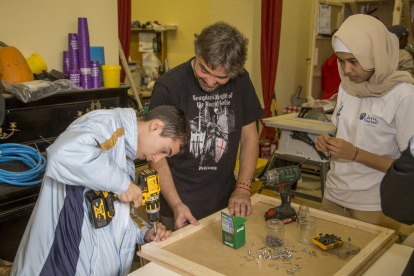 Dos alumnos aprenden nociones de carpintería de la mano de un vecino del Secà. 