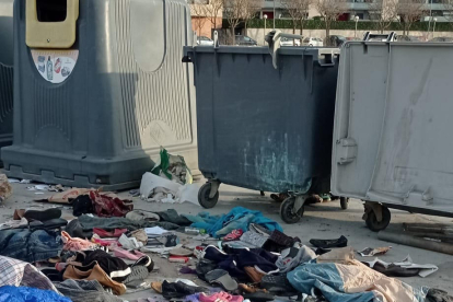 Restos de ropa de un mercadillo tirados junto a contenedores.