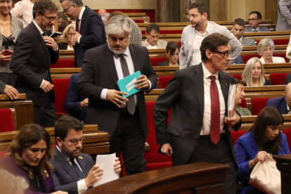 El presidente del grupo parlamentario de Junts, Albert Batet, pasando en el hemiciclo por el lado del presidente de la Generalitat, Pere Aragonès, y el líder del PSC, Salvador Illa, alejándose.