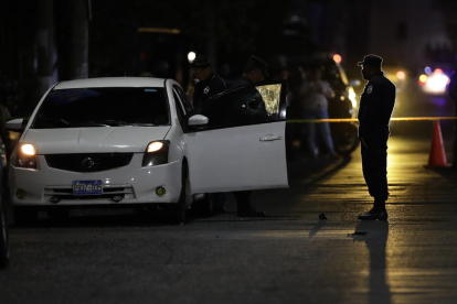 Policías inspeccionan un coche donde ocurrió un asesinato.