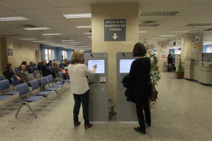 Dos contribuyentes recogen su número para ser atendidas en una oficina de la Agencia Tributaria.