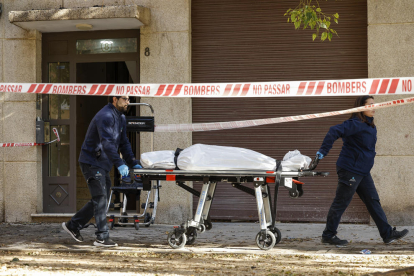 Operarios del retén fúnebre trasladan uno de los cadáveres.