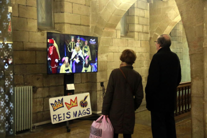 Dues persones miren un vídeo a la mostra 'Els Reis. Los Reixos de Lleida' al pati de la Paeria de Lleida