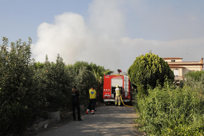 Imatge de la columna de fum (esquerra) i de dos bombers treballant en l’extinció del foc (dreta).