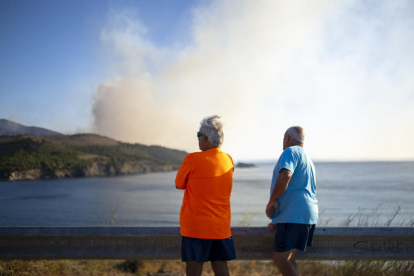 Dos homes observen l’incendi que afecta els municipis de Colera i Portbou, a prop de la frontera amb França.