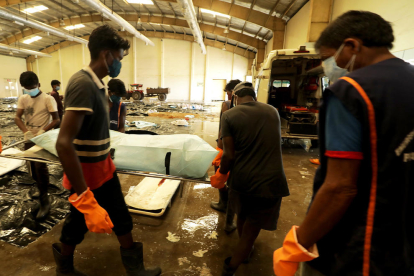 Varias personas buscando a conocidos entre los fallecidos, en una morgue.