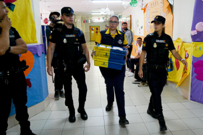 Una funcionària de Correus amb vots escortada per la Policia.