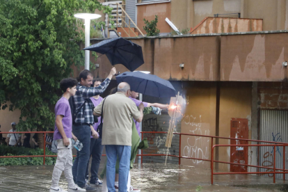 Vecinos de Pius XII, en Lleida ciudad, lanzando el chupinazo de inicio de las fiestas pese a la lluvia.