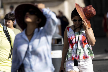 Turistas se tapan del sol durante la última ola de calor.